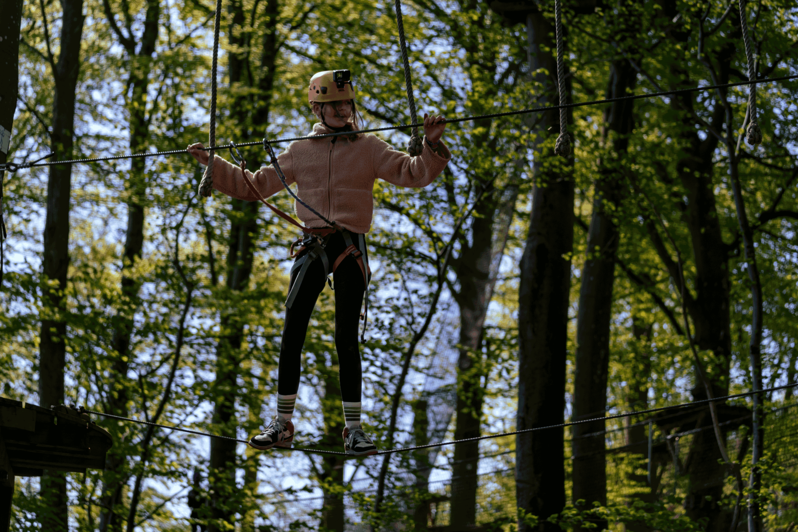 tiener met helm op hoogteparcours tussen de bomen