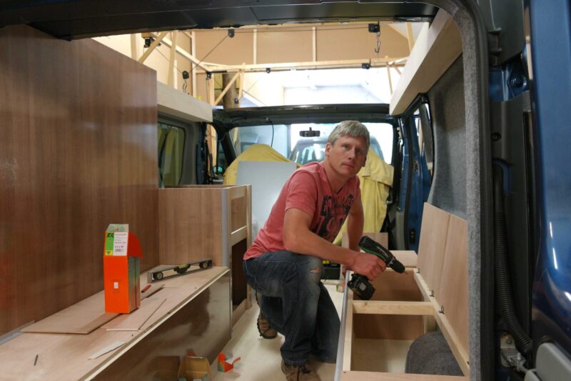 Man bezig met inbouwen van kasten in de camper