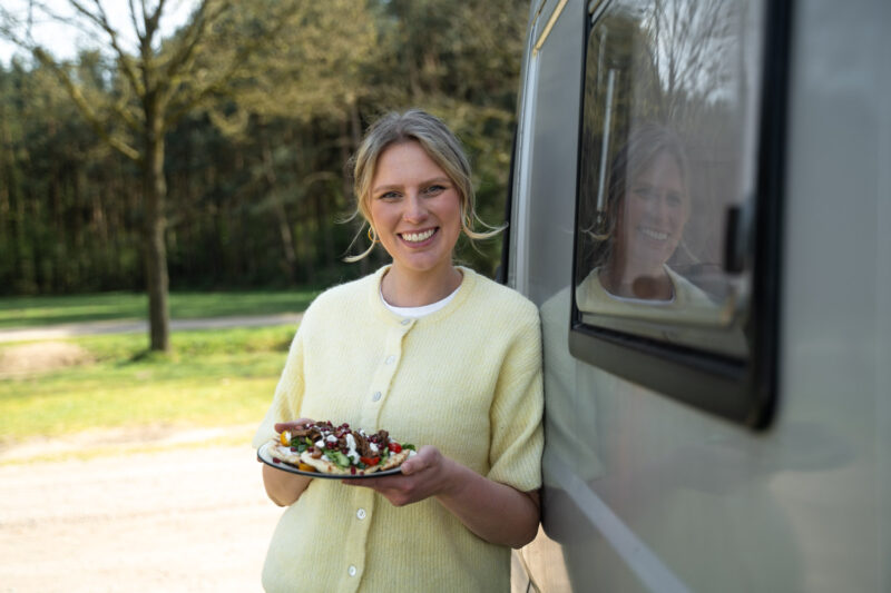 Marieke Plant voor de camper met een bord flatbread met shaorma